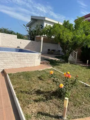 a yard with flowers in the grass in front of a house at Villa Nilić in Bar