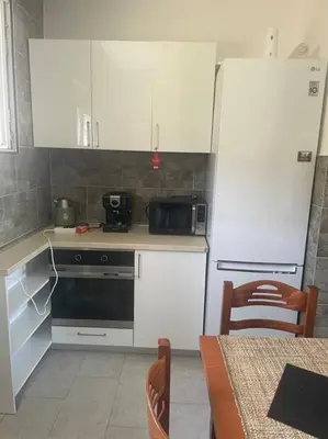 a kitchen with white cabinets and a refrigerator and a table at Villa Nilić in Bar