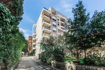 a tall apartment building with trees on the side of a street at Apartments LORA Cetinjska18 in Budva