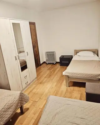 a room with two beds and a door and wooden floors at A&A Apartment in Blue Horizon Przno with pool in Budva