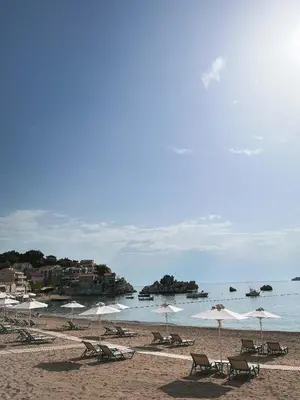a beach with chairs and umbrellas and the ocean at A&A Apartment in Blue Horizon Przno with pool in Budva