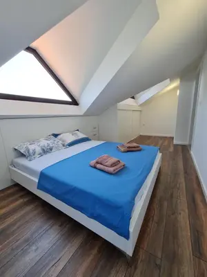 a bedroom with a bed with blue sheets and wooden floors at Luxury Penthouse with panoramic view in Ulcinj