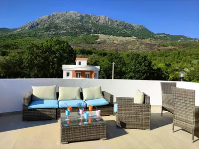 a patio with a couch and chairs and a mountain at Villa Olive Hill in Dobra Voda