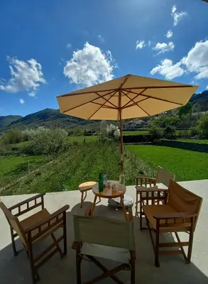 a patio with a table and chairs and an umbrella at Konak Ugnji-Village in Cetinje