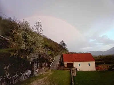 a rainbow over a small white building with a red roof at Konak Ugnji-Village in Cetinje