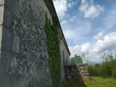 an ivycovered wall with a gate on the side of a building at Country stone house Kovacevic in Danilovgrad