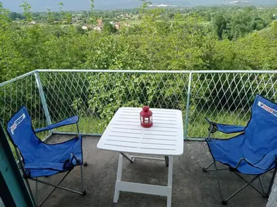 a white table with two chairs and a red vase on it at Country stone house Kovacevic in Danilovgrad