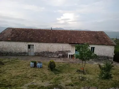 a building with two blue chairs in front of it at Country stone house Kovacevic in Danilovgrad