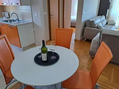 a white table with a bottle and two wine glasses on it at Stan u centru BEST VIEW in Bar