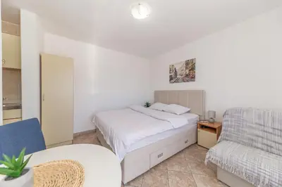 a white bedroom with a bed and a chair at Villa Dana in Bar