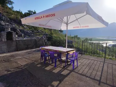 a table with purple chairs and an umbrella at The Island of Prevlaka in Prevlaka