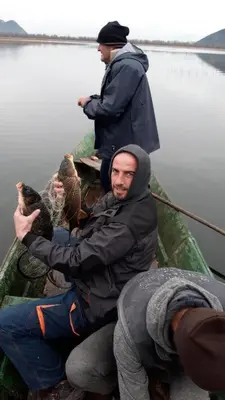 two men sitting in a boat with two birds at The Island of Prevlaka in Prevlaka