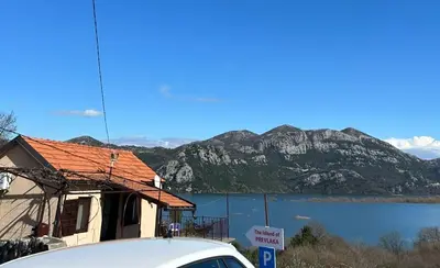 a car parked in front of a house next to a lake at The Island of Prevlaka in Prevlaka