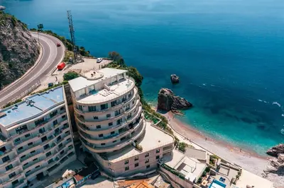 a large building next to a beach with the ocean at Alex Lux sea view aparmtent 2 in Rafailovici