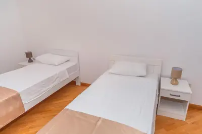 two beds in a room with white walls and wooden floors at Alex Lux sea view aparmtent 2 in Rafailovici