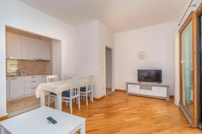 a kitchen and dining room with a table and a television at Alex Lux sea view aparmtent 2 in Rafailovici