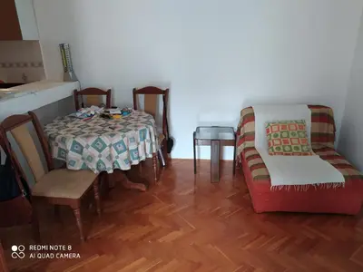 a dining room with a table and two chairs and a table and a couch at Apartman Podkošljun in Budva