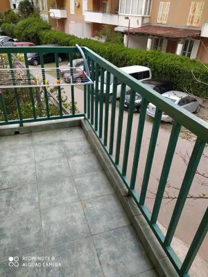 a green railing next to a sidewalk with a parking lot at Apartman Podkošljun in Budva