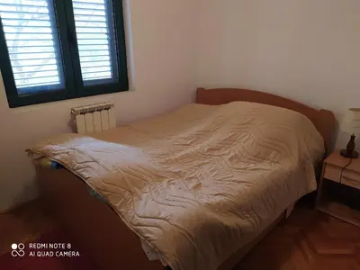 an unmade bed in a room with a window at Apartman Podkošljun in Budva