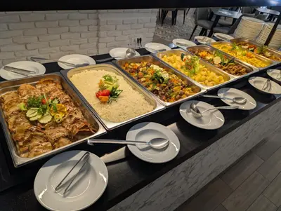 a buffet with several trays of food on a table at Montenegrina Hotel & SPA All-Inclusive in Becici