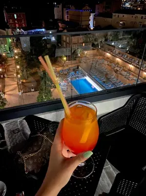 a person holding a drink with a view of a pool at Montenegrina Hotel & SPA All-Inclusive in Becici