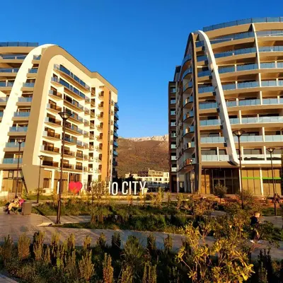two tall buildings in a city with mountains in the background at SOHO JC Apartment in Bar