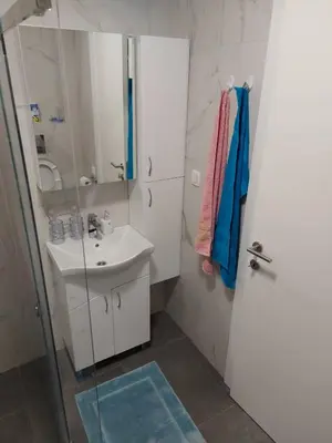 a bathroom with a sink and a glass shower door at SOHO JC Apartment in Bar