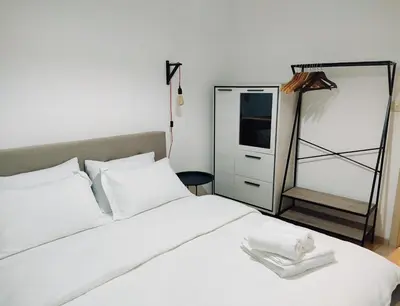 a bedroom with a white bed and a mirror at Vista City Apartment in Podgorica