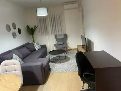 a living room with a couch and a table and a desk at Vista City Apartment in Podgorica