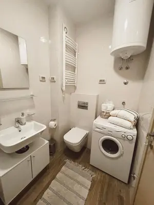a white bathroom with a sink and a washing machine at Vista City Apartment in Podgorica
