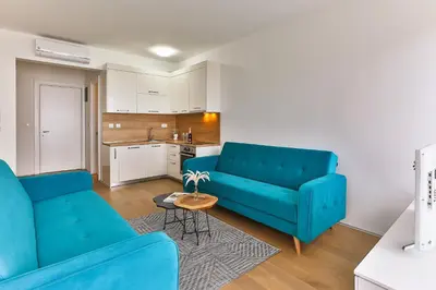 a living room with two blue couches and a kitchen at Royal Residence Apartment in Budva