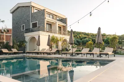 a pool with chairs and umbrellas next to a building at Carolea Villas - Boutique Hotel & Villas in Ulcinj