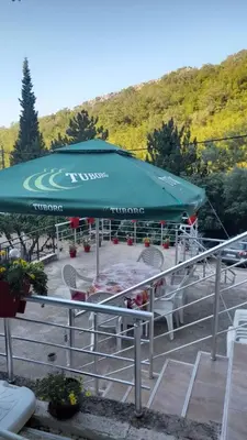 a large green umbrella sitting in a parking lot at Apartmani Momčilović in Čanj