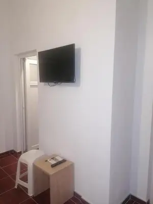 a room with a tv on a wall with a stool at Apartmani Momčilović in Čanj