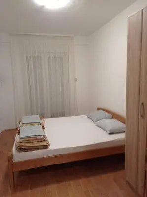 a bedroom with a bed with white sheets and a window at Apartmani Ljumović Budva in Budva