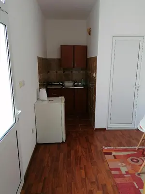 a kitchen with a white refrigerator and wooden floors at Apartmani Ljumović Budva in Budva