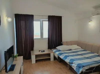 a small bedroom with a bed and a television at Apartmani Durovic in Bar