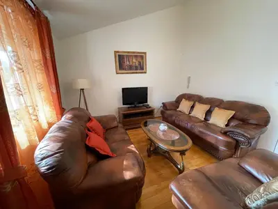 a living room with a leather couch and a table at Aquarium Apartment Kotor in Kotor