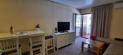 a living room with a television and a table with chairs at Ambassador Apartments in Petrovac na Moru