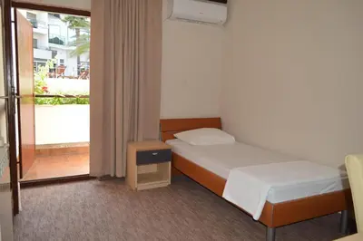 a small bedroom with a bed and a balcony at Ambassador Apartments in Petrovac na Moru