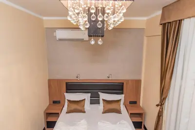 a bedroom with a bed with a chandelier at Hotel Crnogorska Kuća in Podgorica