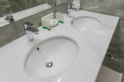 a white bathroom sink with two sinks and candles on it at Hotel Crnogorska Kuća in Podgorica