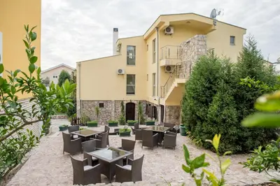 a building with tables and chairs in front of it at Hotel Crnogorska Kuća in Podgorica