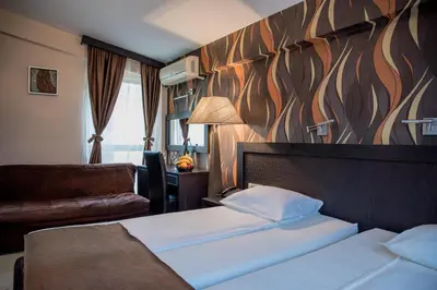 a hotel room with two beds and a couch at Hotel Crnogorska Kuća in Podgorica