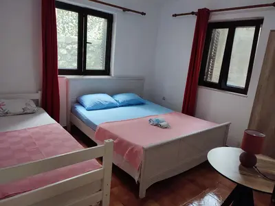 a bedroom with two beds and a table and windows at Bay Mola Aparts in Kotor