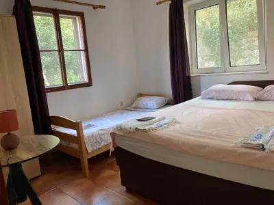 a bedroom with two beds and a table and two windows at Bay Mola Aparts in Kotor