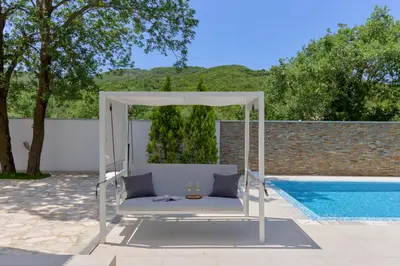 a white swing bed next to a swimming pool at Villa Garden with Private Outdoor Pool in Kotor
