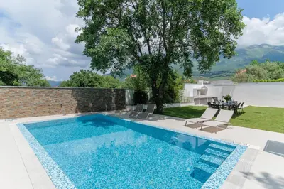 a swimming pool with two chairs and a tree at Villa Garden with Private Outdoor Pool in Kotor