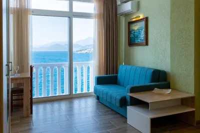a living room with a blue couch and a large window at DreamSea Apartment in Utjeha