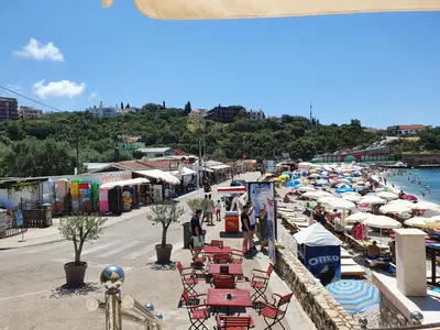 a beach with a bunch of chairs and umbrellas at DreamSea Apartment in Utjeha